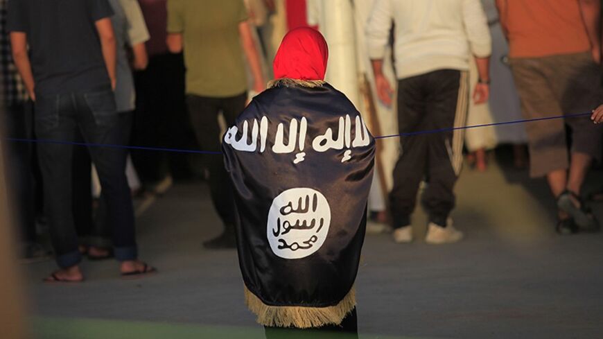 A girl with a flag draped over her shoulders watches as people gather for a demonstration over the capture of senior al Qaeda figure Abu Anas al-Liby by U.S. authorities, in Benghazi October 11, 2013. Libyan citizen Al-Liby, whose real name is Nazih al-Ragye, is a suspect in the 1998 bombings of U.S. embassies in Kenya and Tanzania that killed 224 civilians. Since his capture in Tripoli last week, he has been held aboard a Navy ship in the Mediterranean where an elite team of American interrogators is quest