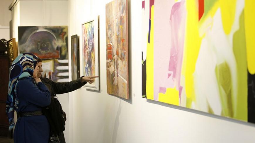 Visitors look at paintings during an art exhibition in Baghdad December 2, 2013. As part of its role as Capital of Arab culture of 2013, Baghdad hosted the three-day art exhibition featuring more than 500 sculptures and paintings of Iraqi and Arab artists. Artists from Syria, Lebanon and Morocco participated in the event which is considered the first of its kind since 1980s. Baghdad was named the 2013 Arab Capital of Culture by the Arab League, but the worst wave of bombings in Iraq in five years is taking 