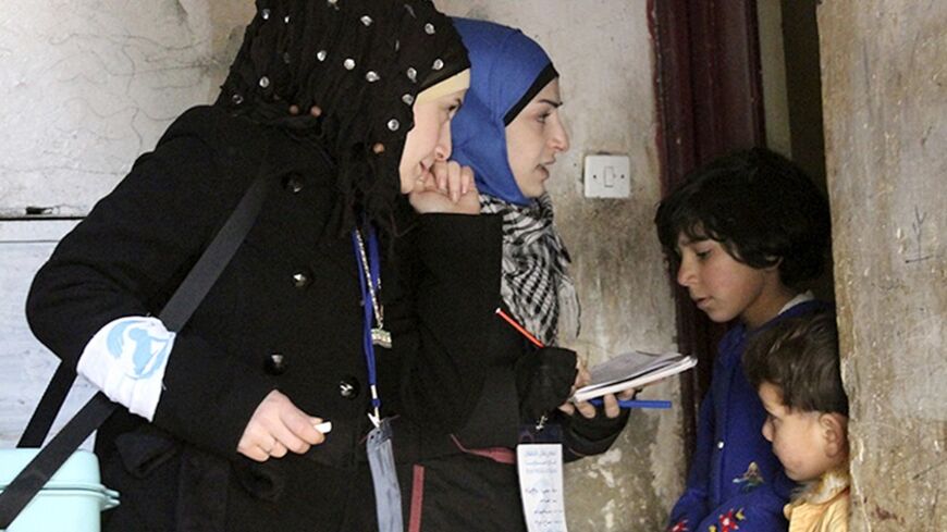 Activist health workers speak to family members before administering polio vaccinations in Aleppo January 5, 2014. In November last year, the World Health Organisation (WHO) said 13 cases had been found in the largely rebel-held province of Deir al-Zor - where polio broke out in 2013. Two more have since been recorded there and the virus has surfaced in Aleppo city and near Damascus, the first outbreak since 1999 in Syria, where civil war has raged since a crackdown on protests in 2011. REUTERS/Hosam Katan 