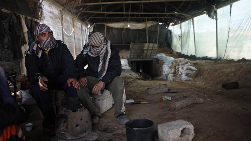 Tunnel workers sit outside a smuggling tunnel on the border between Egypt and the southern Gaza Strip February 17, 2014. Voices of construction workers and the noise from their tools used to ring out in Gaza's streets. Now hulks of unfinished buildings stand in eerie silence, and the idle builders are left to worry how to make ends meet. An Egyptian-Israeli blockade on Gaza, run by the Hamas Islamist movement, has left industry and construction gasping for resources, pushing unemployment to dizzying heights