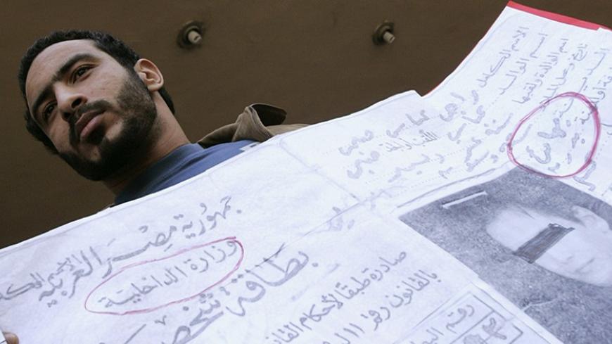 A demonstrator holds placards featuring Baha'i identity cards at a protest in front of the Court of the State Council in Cairo December 16, 2006, to show support for the Baha'i community in Egypt. An Egyptian court on Saturday overturned a lower court ruling that gave the country's small Baha'i community the right to identify themselves as Baha'is on official documents such as identity cards. REUTERS/Nasser Nuri (EGYPT) - RTR1KGZW