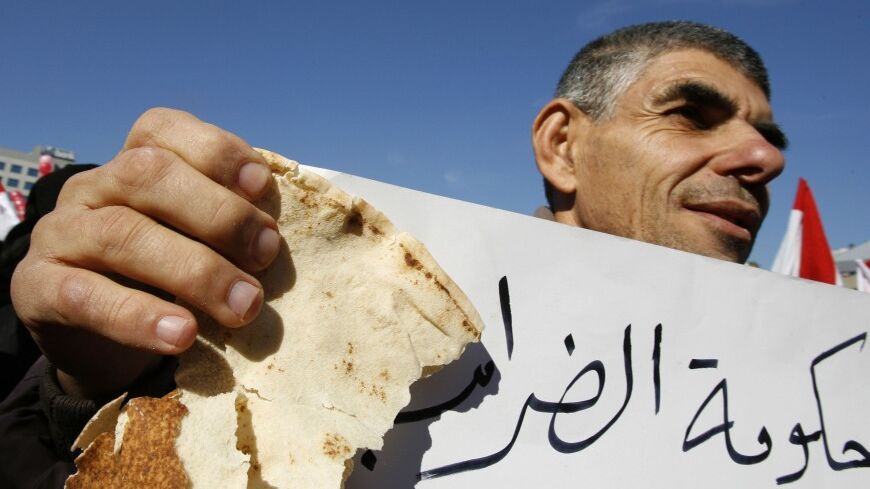 A protester carries a piece of bread and an anti-government banner during a Hezbollah-backed protest against the government's economic reform programme outside the tax office in Beirut January 9, 2007.   REUTERS/Jamal Saidi (LEBANON) - RTR1L0JU