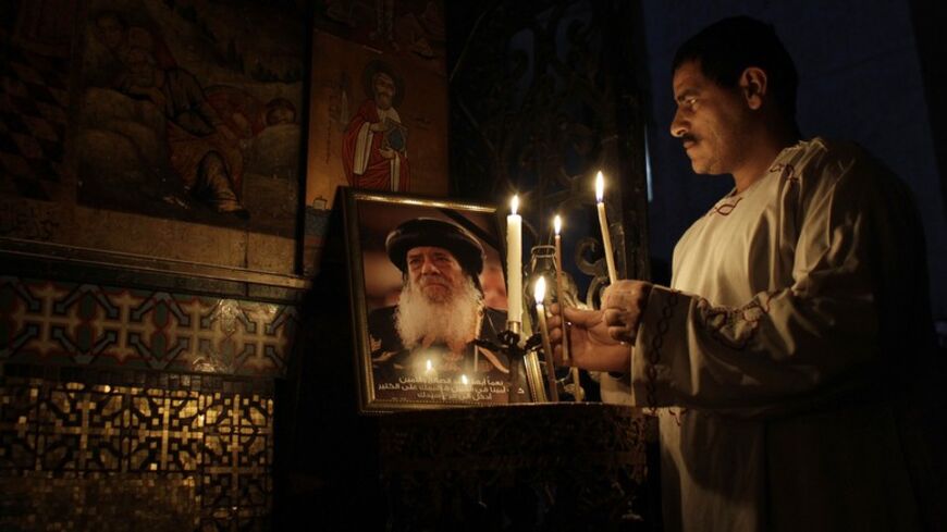 A Coptic Christian priest holds candles next to a picture of Egyptian Coptic Christian Pope Shenouda III in the Church of the Holy Sepulchre in Jerusalem's Old City March 18, 2012. Pope Shenouda III, the patriarch of most of Egypt's estimated 12 million Christians, died on Saturday from old age, his political adviser told Reuters. REUTERS/Ammar Awad (JERUSALEM - Tags: RELIGION OBITUARY) - RTR2ZJJF