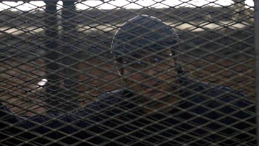 Activist Ahmed Maher stands behind bars at a court in Cairo April 7, 2014. An Egyptian appeals court on Monday upheld the jailing of three leading figures of the 2011 pro-democracy uprising, tightening a crackdown on secular activists opposed to the army-backed government. A court handed down three-year sentences on Monday to the three liberal activists, Ahmed Maher, Ahmed Douma and Mohamed Adel, last December for protesting without permission and assaulting the police. REUTERS/Al Youm Al Saabi Newspaper (E