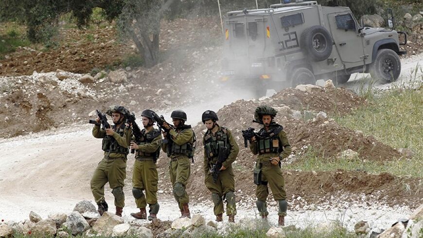 Israeli soldiers check their weapons at a staging near the West Bank city of Hebron April 15, 2014. An Israeli man was killed in a shooting attack on a civilian car near the city of Hebron in the occupied West Bank on Monday, the eve of the Jewish holiday of Passover, military sources said.
 REUTERS/Ammar Awad (WEST BANK - Tags: POLITICS CIVIL UNREST MILITARY TPX IMAGES OF THE DAY) - RTR3LCE0