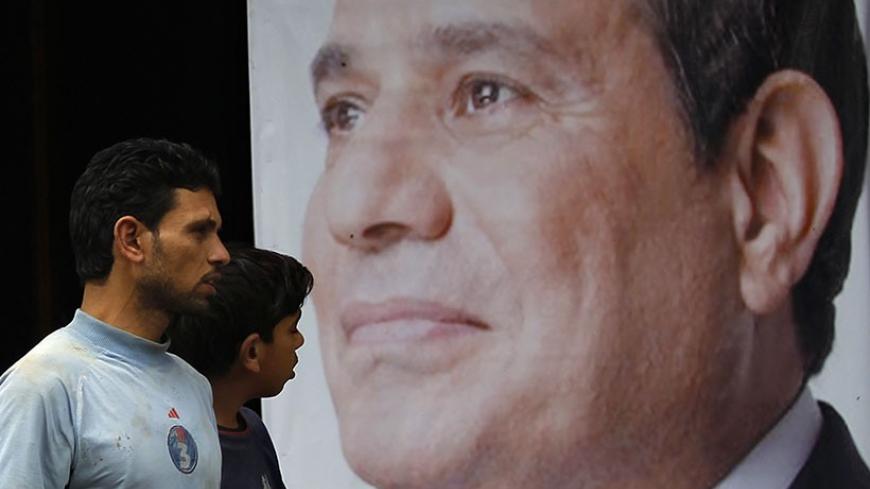 People walk past a poster of presidential candidate and former army chief Abdel Fattah al-Sisi at one of his campaign headquarters in central Cairo April 16, 2014. Egyptians will vote on May 26-27 in a presidential election where Abdel Fattah al-Sisi is expected to win easily. REUTERS/Amr Abdallah Dalsh   (EGYPT - Tags: POLITICS ELECTIONS) - RTR3LLFJ