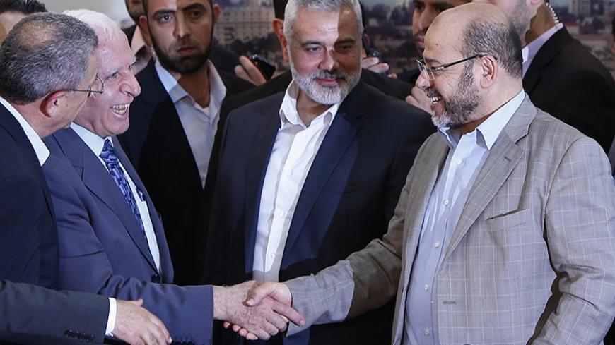 Senior Fatah official Azzam Al-Ahmed (L) shakes hands with senior Hamas leader Moussa Abu Marzouq after announcing a reconciliation agreement in Gaza City April 23, 2014. The Gaza-based Islamist group Hamas and President Mahmoud Abbas's Palestine Liberation Organization (PLO) agreed on Wednesday to implement a unity pact, both sides announced in a joint news conference.REUTERS/Suhaib Salem (GAZA - Tags: POLITICS) - RTR3MBRU