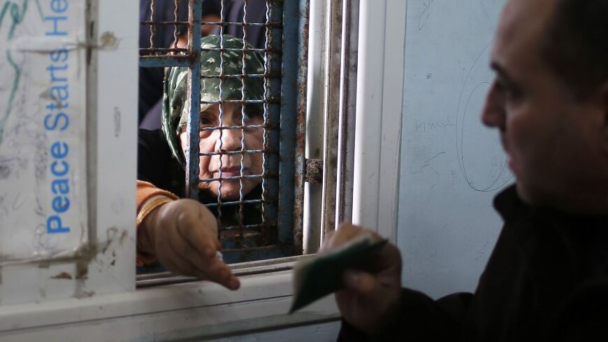 A Palestinian woman presents her identification as she waits to receive food supplies from a United Nations food distribution centre in Gaza City December 19, 2013. Almost a million people are expected to need food aid in the Gaza Strip next year, a U.N. agency said on Wednesday as it appealed for $95 million from donors. REUTERS/Mohammed Salem (GAZA - Tags: POLITICS SOCIETY) - RTX16O8Y