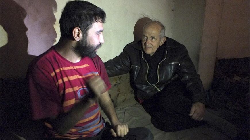 Dutch Jesuit Father Frans van der Lugt (R) talks with a man in the besieged area of Homs, January 30, 2014. Van der Lugt, who is living in the besieged area, made an appeal for help on a YouTube video few days ago, shedding light on the conditions inside, which is suffering severe food and medical shortages.  REUTERS/Yazan Homsy (SYRIA - Tags: POLITICS CIVIL UNREST RELIGION) - RTX181GR