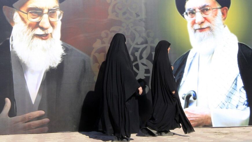 Iraqi women walk past a poster depicting images of Shi'ite Iran's Supreme Leader Ayatollah Ali Khamenei at al-Firdous Square in Baghdad February 12, 2014. An Iraqi daily newspaper stopped publishing after two bombs were planted in the entrance to its headquarters in Baghdad on Monday and after threats from an Iranian-backed Shi'ite militia. Editors and reporters at Assabah AlJadeed said they had received death threats from the influential Asaib al-Haq militia in response to what it had described as an "insu