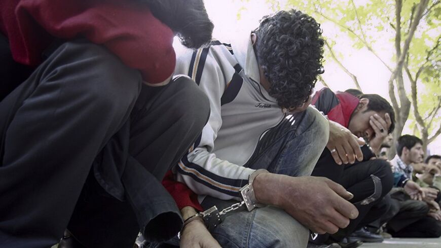 Handcuffed suspects sit on the ground after officers arrest and detain suspected drug users and dealers during a sweep in a southern neighbourhood of Tehran April 7, 2009. Iran lies in the middle of the transit route of drugs from Afghanistan to Europe. REUTERS/Jamejam Online/Chavosh Homavandi (IRAN CONFLICT SOCIETY POLITICS) - RTXDQR5