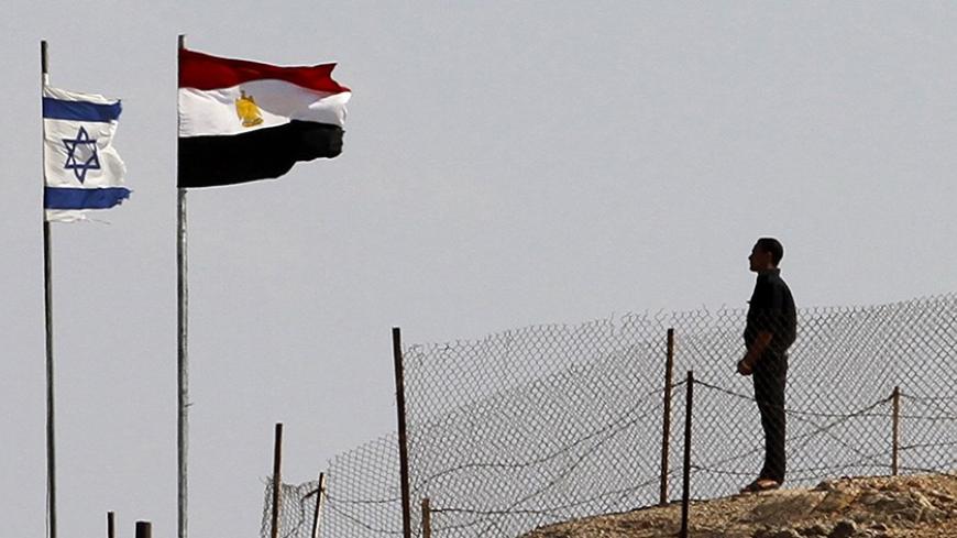 An Egyptian soldier stands near the Egyptian national flag and the Israeli flag at the Taba crossing between Egypt and Israel, about 430 km (256 miles) northeast of Cairo, October 26, 2011. Israel and Egypt said on Monday they have struck a deal to swap 25 Egyptians in Israeli custody for a U.S.-Israeli dual national accused by Cairo of espionage, in a step seen as easing strains between the strategic neighbors. REUTERS/Mohamed Abd El-Ghany  (EGYPT - Tags: CIVIL UNREST POLITICS) - RTR2T7XN