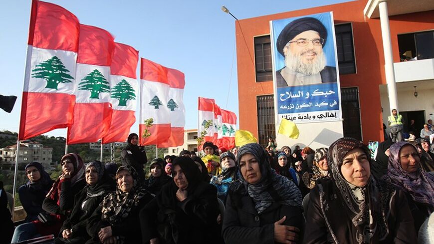Hezbollah supporters stand in front of a giant banner of their leader Sayyed Hassan Nasrallah as they listen to his speech, in Aineta village, in south Lebanon March 29, 2014. Hezbollah leader Sayyed Hassan Nasrallah on Saturday called for domestic support for his militants after a year of growing sectarian violence in Lebanon following the Shi'ite militant group's intervention in the Syrian war. REUTERS/ Sharif Karim (LEBANON - Tags: POLITICS CIVIL UNREST) - RTR3J41G