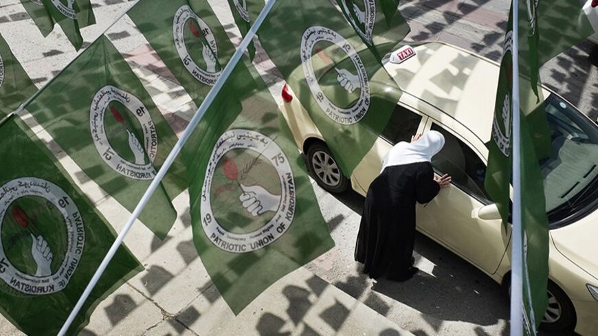 A woman hails a taxi while standing under Patriotic Union of Kurdistan (PUK) logos before Iraq's parliamentary elections in Sulaimaniya April 28, 2014. Picture taken April 28, 2014. To match IRAQ-ELECTION/KURDS REUTERS/Jacob Russell (IRAQ - Tags: ELECTIONS POLITICS) - RTR3N0GY