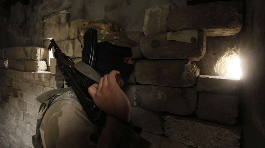 A member of the Islamic State of Iraq and the Levant carries his weapon as he looks through a hole in a wall in Sheikh Saeed neighbourhood December 4, 2013. REUTERS/Molhem Barakat (SYRIA - Tags: POLITICS CIVIL UNREST CONFLICT MILITARY) - RTX163J6