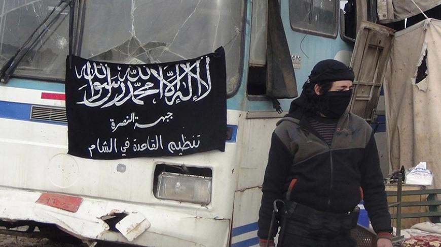 A member of Islamist Syrian rebel group Jabhat al-Nusra mans a checkpoint on the border crossing between Syria and Jordan, which they claim to have taken control of, in Daraa December 26, 2013. Flag reads, "There is no God but Allah, and Muhammad is his prophet. Al-Nusra front, al-Qaeda in the Levant". Picture taken December 26, 2013. REUTERS/Ammar Khassawneh (SYRIA - Tags: POLITICS CIVIL UNREST CONFLICT) - RTX16VW7