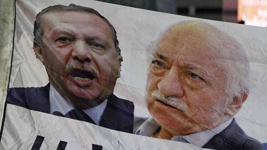 A demonstrator hold pictures of Turkey's Prime Minister Tayyip Erdogan and Turkish cleric Fethullah Gulen (R), during a protest against Turkey's ruling AK Party (AKP), demanding the resignation of Erdogan, in Istanbul December 30, 2013. Erdogan swore on Sunday he would survive a corruption crisis circling his cabinet, saying those seeking his overthrow would fail just like mass anti-government protests last summer. Gulen denies involvement in stirring up the graft case, but he regularly censures Erdogan, a