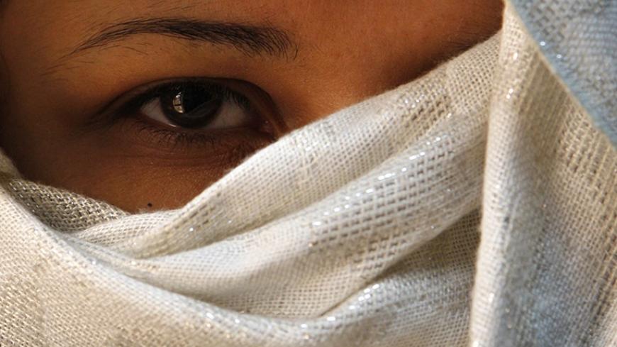 A woman who was abused by her husband covers her face, so as not to be identified by her family, at the Sisterhood Is Global Institute office in Amman March 5, 2009, ahead of the International Day for the Elimination of Violence against Women.    REUTERS/Ali Jarekji (JORDAN) - RTXCDU6