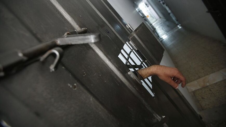 The hand of an alleged Palestinian collaborator hangs out of his cell as he speaks with a security guard inside a Hamas-run prison in Gaza City April 23, 2013. The Islamist Hamas government, which is pledged to Israel's destruction by force of arms, is lauding a recent campaign to root out informants in its midst, which it hopes will deprive Israel of a subtle but effective tool. Picture taken April 23, 2013. To match Feature PALESTINIANS-HAMAS/SPIES   REUTERS/Suhaib Salem (GAZA - Tags: POLITICS) - RTXZEXX
