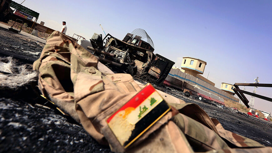 The jacket belonging to an Iraqi Army uniform lies on the ground in front of the remains of a burnt out Iraqi army vehicle close to the Kukjali Iraqi Army checkpoint, some 10km of east of the northern city of Mosul, on June 11, 2014, the day after Sunni militants, including fighters from the Islamic State of Iraq and the Levant (ISIL) overran the city. Half a million people were estimated to have fled Iraq's second largest city, as Islamist militants tightened their grip after overrunning it and a swathe o