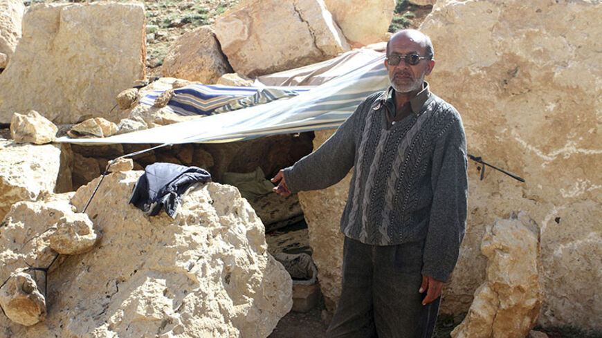A Syrian refugee points at his make-shift home in Tfail village in Bekaa Valley after fleeing the violence in Syria, April 22, 2014.  The only accessible road to the Lebanese border village of Tfail, cut off by Syrian regime troops as part of the regime's offensive to root out rebels in the Qalamoun region, was reopened on Tuesday by the Lebanese Army. REUTERS/Ahmad Shalha (LEBANON - Tags: POLITICS CIVIL UNREST) - RTR3M9R6