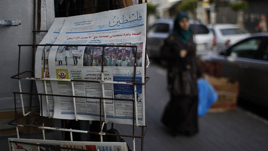 A Palestinian woman walks past copies of a pro-Hamas newspaper, Palestine, displayed outside a shop in the West Bank city of Ramallah May 10, 2014. The Palestinian authority had allowed the distribution of the pro-Hamas Palestine newspaper in the West Bank on Saturday after the Hamas-run government in the Gaza Strip said on Wednesday it had relaxed a ban on Palestinian newspapers published outside the enclave as a gesture of reconciliation to rival group Fatah after their unity deal last month. REUTERS/Moha