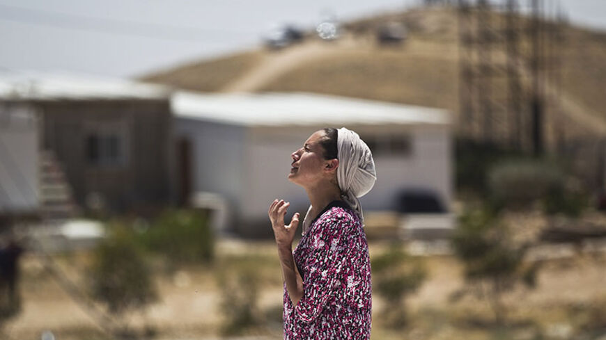 A Jewish settler reacts as she stands atop the roof of a temporary structure before Israeli policemen demolish it in the West Bank Jewish settler outpost of Maale Rehavam, near Bethlehem May 14, 2014. Some seven structures were razed on Wednesday by Israeli border police officers and no injuries or arrests were made during the incidences, a police spokesman said on Wednesday. The structures were demolished as part of Israel's continuing effort to remove settlements built without government authorization. R