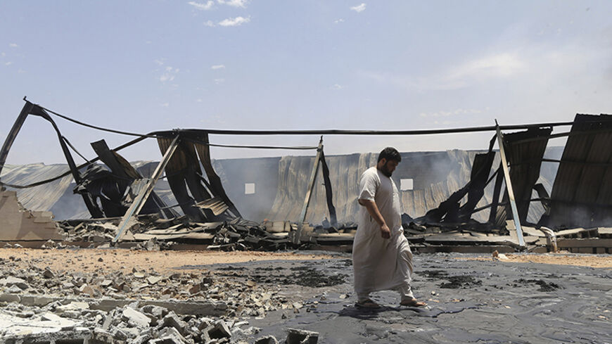 A man walks past destroyed warehouses following Friday's clashes between Libyan irregular forces and Islamist militias in the eastern city of Benghazi May 17, 2014. REUTERS/Esam Omran Al-Fetori (LIBYA - Tags: CIVIL UNREST POLITICS) - RTR3PL90