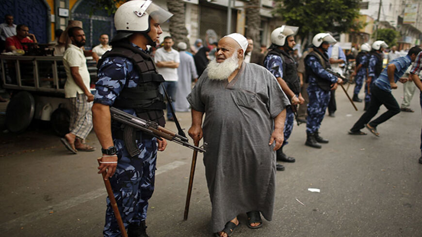 A Palestinian employee paid by Palestinian Authority stands next to a policeman as he waits to receive his salary outside a closed bank in Gaza City June 5, 2014. A Palestinian unity government formed by President Mahmoud Abbas and the Islamist Hamas group faced its first and serious challenge on Thursday when civil servants of Hamas, who were not on the payment list, scuffled with those cashing their salaries. Civil servants employed by Hamas since 2007 arrived and prevented employees paid by the Palestini