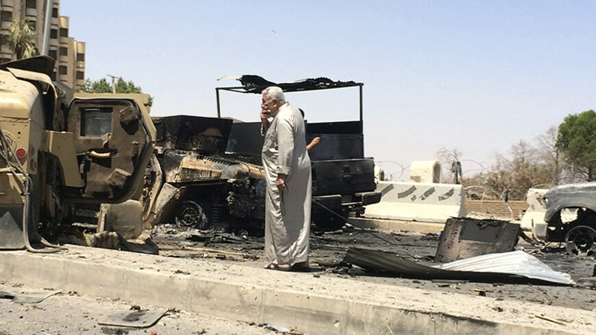 A man looks at burnt vehicles belonging to Iraqi security forces one day after radical Sunni Muslim insurgents seized control of city of Mosul June 11, 2014. Sunni insurgents from an al Qaeda splinter group extended their control from the northern city of Mosul on Wednesday to an area further south that includes Iraq's biggest oil refinery in a devastating show of strength against the Shi'ite-led government. REUTERS/Stringer (IRAQ - Tags: CIVIL UNREST POLITICS CRIME LAW) - RTR3T884