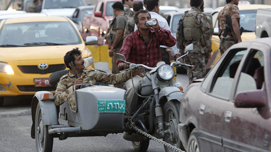 People ride a motorcycle belonging to the Iraqi army at a Kurdish military checkpoint on the outskirts of the northern Iraqi city of Kirkuk June 11, 2014. Kurdish forces initially attempted to stop people driving vehicles looted from the Iraqi army at the checkpoint but eventually let them through as there were too many of them. Sunni insurgents from an al Qaeda splinter group extended their control from the northern city of Mosul on Wednesday to an area further south that includes Iraq's biggest oil refine