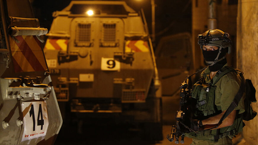 An Israeli soldier stands guard in the West Bank city of Hebron June 15, 2014. Israel sent more troops to the occupied West Bank on Saturday to step up searches for three Israeli teenagers believed to have been abducted by Palestinians, with a military source saying it was not known if they were dead or alive.REUTERS/ Mussa Qawasma (WEST BANK - Tags: MILITARY) - RTR3TUFF