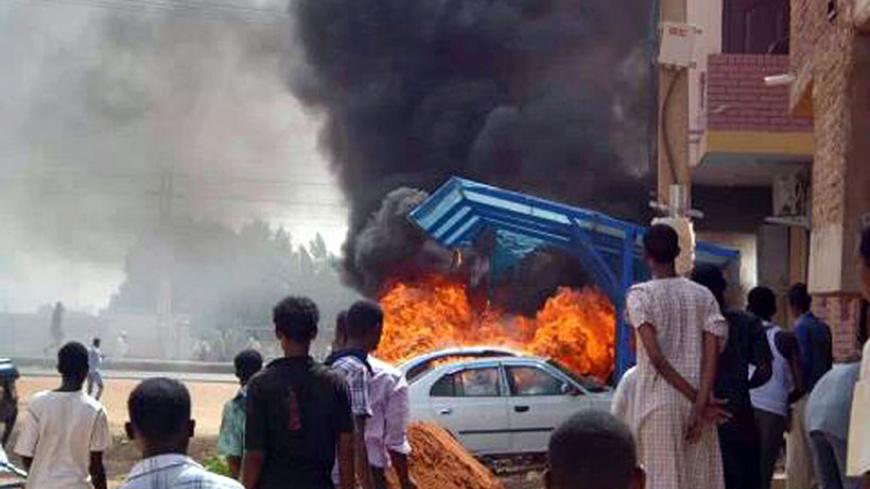 People look at burning cars during protests over fuel subsidy cuts in Khartoum September 25, 2013. At least 27 people have been killed in protests in Khartoum over fuel subsidy cuts, a medical source said on Thursday as another bout of the worst unrest seen in Sudan's relatively well-off central regions for years broke out in its biggest port. Thousands had marched in Khartoum on Wednesday, torching cars, buildings and petrol stations. Picture taken September 25, 2013. REUTERS/Stringer (SUDAN - Tags: CIVIL 