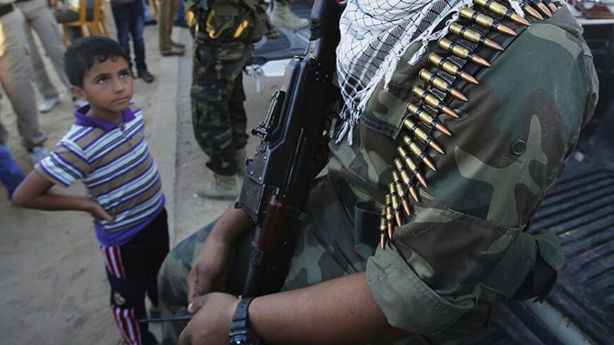 A Palestinian boy looks at a militant during an anti-Israel rally organized by Islamic Jihad movement in Rafah in the southern Gaza Strip October 24, 2013. REUTERS/Suhaib Salem (GAZA - Tags: POLITICS CIVIL UNREST TPX IMAGES OF THE DAY) - RTX14MNS