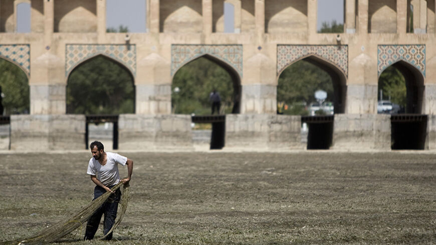 A fisherman tries to catch fish at the dried-up Zayanderood River, with the Khajoo Bridge seen in the background, in Isfahan, 450 km (281 miles) south of Tehran, June 27, 2008. The river dried up due to low rainfall and the water being re-channelled for hydroelectricity purposes. REUTERS/Morteza Nikoubazl (IRAN) - RTX7EU6