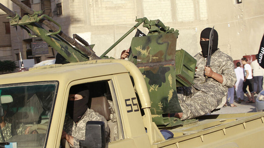 Militant Islamist fighters travel in a vehicle as they take part in a military parade along the streets of Syria's northern Raqqa province June 30, 2014. The fighters held the parade to celebrate their declaration of an Islamic "caliphate" after the group captured territory in neighbouring Iraq, a monitoring service said. The Islamic State, an al Qaeda offshoot previously known as Islamic State in Iraq and the Levant (ISIL), posted pictures online on Sunday of people waving black flags from cars and holding