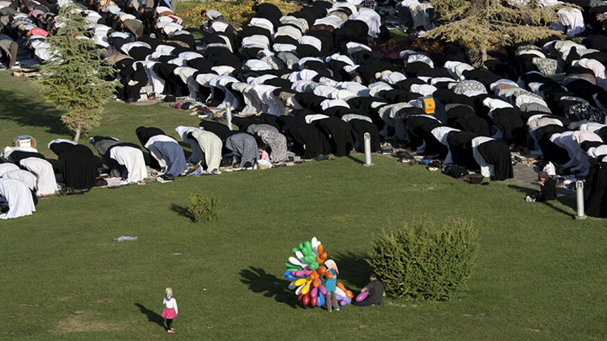 Iranian vendors inflate balloons as a girl observes women kneeling in prayer at the historical Naqsh-e Jahan Square in Isfahan on August 31, 2011 on the first day of Eid al-Fitr in the predominantly Shiite Muslim Iran, marking the end of the holy fasting month of Ramadan. AFP PHOTO/BEHROUZ MEHRI (Photo credit should read BEHROUZ MEHRI/AFP/Getty Images)