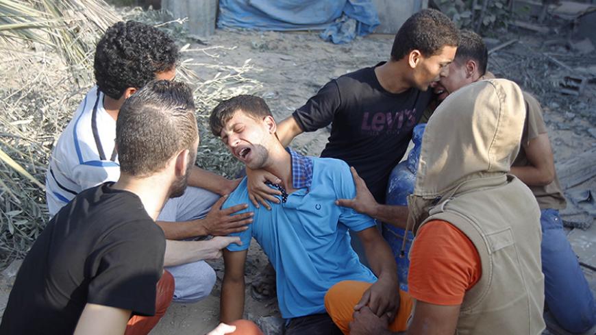 Palestinian relatives mourn for victims of the Duheir family, near the rubble of their home, after it was destroyed by an Israeli air strike in Rafah on July 29, 2014, in the southern of Gaza strip. Bloodshed in war-torn Gaza surged with dozens more Palestinians killed as the conflict raged into a fourth week and Iran accused Israel of genocide in the tiny enclave.  AFP PHOTO/ SAID KHATIB        (Photo credit should read SAID KHATIB/AFP/Getty Images)