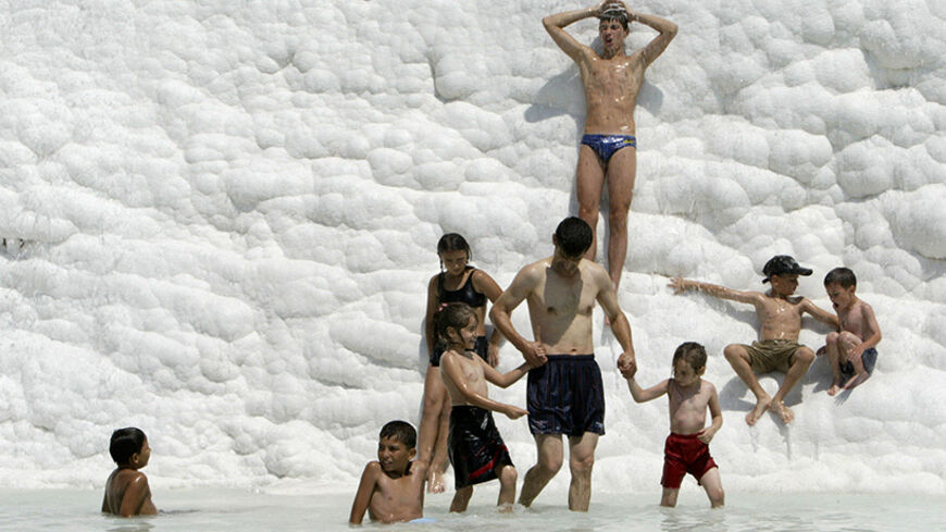 DENIZLI, TURKEY:  Tourists enjoy the travertine pools in Pamukkale visited by thousands every year located 20 kilometers from the town of Denizli nearby ancient city Hierapolis western Turkey, 19 August 2004. Pamukkale (Cotton Castle) is a white cascade from sources containing chalky water which formed stalactites, basins and terraces. The calcium-rich water is renown for its healing qualities for eye and skin diseases, for softening rheumatism, asthma and dermatitis crisis. Today is not allowed any more to