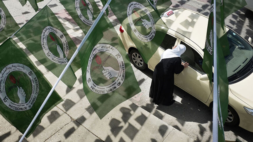A woman hails a taxi while standing under Patriotic Union of Kurdistan (PUK) logos before Iraq's parliamentary elections in Sulaimaniya April 28, 2014. Picture taken April 28, 2014.        To match IRAQ-ELECTION/KURDS      REUTERS/Jacob Russell (IRAQ - Tags: ELECTIONS POLITICS) - RTR3N0GY