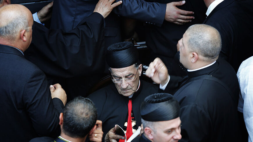 Maronite Patriarch Beshara al-Rai reads as he is surrounded by security personnel during his a visit to Birim, a northern Israeli village whose Maronite Christian residents were displaced 66 years ago May 28, 2014. The Lebanese church leader who defied warnings from the powerful Shi'ite Muslim Hezbollah movement by accompanying the Pope on a Holy Land visit pledged on Wednesday to help dispossessed Christians in Israel. REUTERS/Finbarr O'Reilly (ISRAEL - Tags: RELIGION POLITICS TPX IMAGES OF THE DAY) - RTR