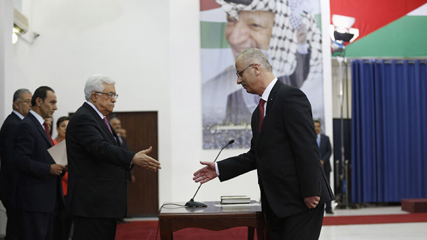Palestinian Prime Minister Rami Hamdallah (R) shakes hands with Palestinian President Mahmoud Abbas during a swearing-in ceremony of the unity government, in the West Bank city of Ramallah June 2, 2014. Abbas swore in a unity government on Monday after overcoming a last-minute dispute with the Hamas Islamist group.
REUTERS/Mohamad Torokman (WEST BANK - Tags: POLITICS) - RTR3RT5M