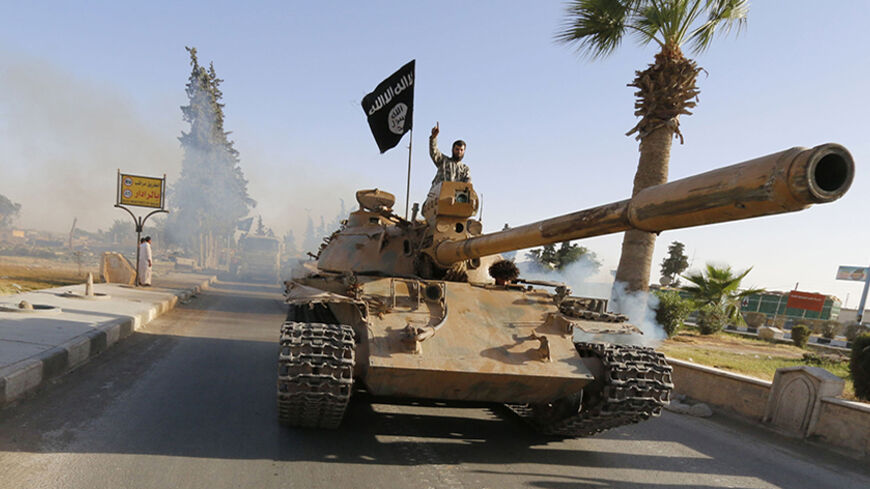 Militant Islamist fighters on a tank take part in a military parade along the streets of northern Raqqa province June 30, 2014. Militant Islamist fighters held a parade in Syria's northern Raqqa province to celebrate their declaration of an Islamic "caliphate" after the group captured territory in neighbouring Iraq, a monitoring service said. The Islamic State, an al Qaeda offshoot previously known as Islamic State in Iraq and the Levant (ISIL), posted pictures online on Sunday of people waving black flags 