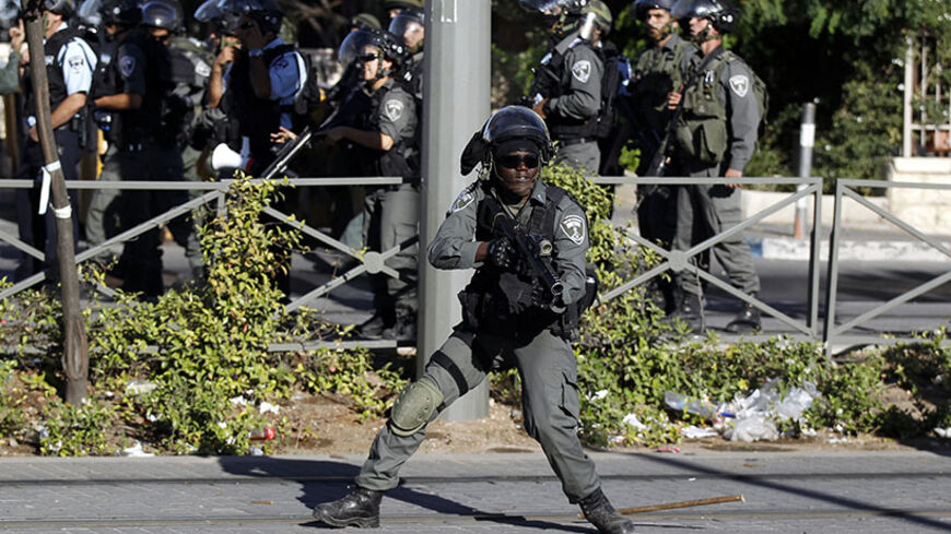 An Israeli border police officer takes up position during clashes with Palestinian stone-throwers in Shuafat, an Arab suburb of Jerusalem July 2, 2014. The discovery of a body in a Jerusalem forest on Wednesday raised suspicions that a missing Palestinian youth had been killed by Israelis avenging the deaths of three abducted Jewish teens. Rock-throwing Palestinians clashed with Israeli forces in Jerusalem after the news, but no serious injuries were reported. REUTERS/Ammar Awad (JERUSALEM - Tags: POLITICS