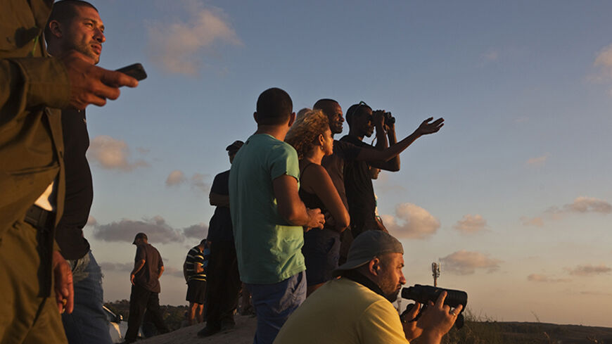 Israelis look over the northern Gaza Strip from a lookout hill near Sderot July 13, 2014. Thousands fled their homes in a Gaza town on Sunday after Israel warned them to leave ahead of threatened attacks on rocket-launching sites, on the sixth day of an offensive that Palestinian officials said has killed at least 160 people. Militants in the Hamas-ruled Gaza Strip kept up rockets salvoes deep into the Jewish state and the worst bout of Israel-Palestinian bloodshed in two years showed no signs of abating, a