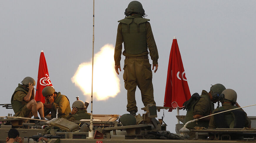 Israeli soldiers stand on an armoured personnel carrier (APC) outside the central Gaza Strip as they fire mortar shell towards Gaza before a ceasefire was due, early August 1, 2014. Israeli shelling near the southern Gaza town of Rafah killed at least 40 people on Friday, the local hospital said, as a ceasefire that went into effect only hours earlier crumbled. Israel accused Hamas and other Palestinian militant groups of violating the U.S.- and U.N.-mediated truce, but did not elaborate, amid Israeli media