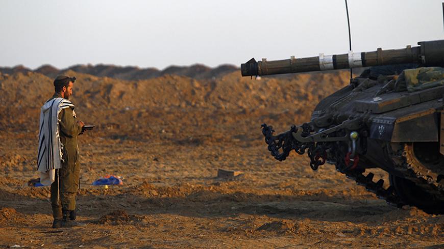 An Israeli soldier prays by a tank at an Israeli Defence Forces (IDF) staging area in the central Gaza border November 21, 2012.  Israeli air strikes shook the Gaza Strip and Palestinian rockets struck across the border as U.S. Secretary of State Hillary Clinton held talks in Jerusalem in the early hours of Wednesday, seeking a truce that can hold back Israel's ground troops.  REUTERS/Yannis Behrakis (ISRAEL - Tags: CONFLICT CIVIL UNREST MILITARY RELIGION) - RTR3AOGQ