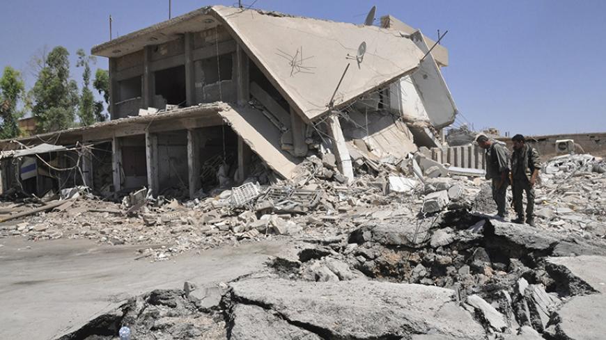Residents inspect damage at a site which activists said was caused by a suicide bomber in the middle of a market last night in Tirbespiye village, east Qamishli, June 15, 2014. Activists claim that 14 people died due to the explosion, seven of them are Arab and the other seven are Kurds, while 25 were injured. REUTERS/Massoud Mohammed (SYRIA - Tags: POLITICS CIVIL UNREST CONFLICT) - RTR3TWNH