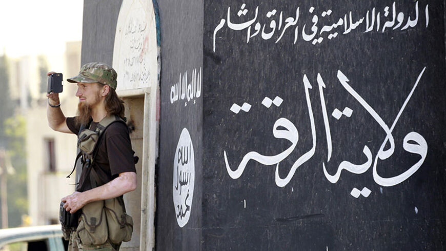 A militant Islamist fighter uses a mobile to film his fellow fighters taking part in a military parade along the streets of Syria's northern Raqqa province June 30, 2014. The fighters held the parade to celebrate their declaration of an Islamic "caliphate" after the group captured territory in neighbouring Iraq, a monitoring service said. The Islamic State, an al Qaeda offshoot previously known as Islamic State in Iraq and the Levant (ISIL), posted pictures online on Sunday of people waving black flags from