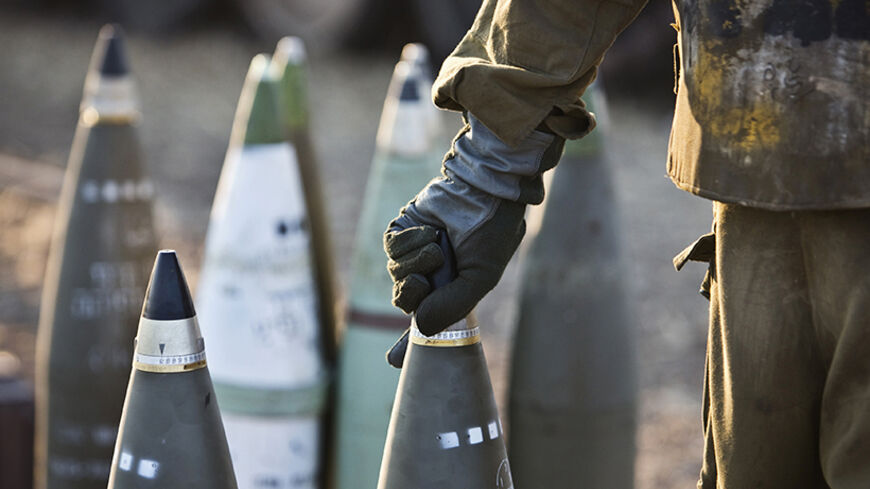 An Israeli soldier lifts a shell at a site where mobile artillery units are deployed, outside the Gaza Strip July 21, 2014. The Palestinian death toll in an Israeli offensive in the Gaza Strip jumped to more than 500 on Monday, as the United States, alarmed by escalating civilian bloodshed, took a direct role in efforts to secure a ceasefire. Israel's losses also mounted. Following the death of 13 soldiers on Sunday, Israel said seven more troops had died on Monday, including four killed when a group of mil